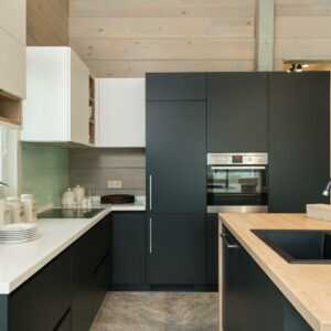 Moderne Küche mit matter, weißer Arbeitsplatte im Dekor FENIX Bianco Kos und natürlichen Holzfronten.