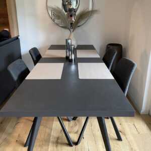 Grauer Esszimmertisch mit weißen Tellerunterlagen, grauen Stühlen und Holzboden