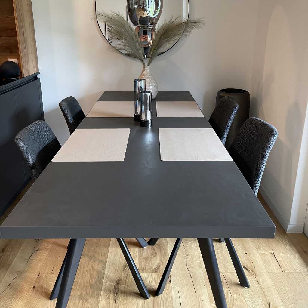 Grauer Esszimmertisch mit weißen Tellerunterlagen, grauen Stühlen und Holzboden