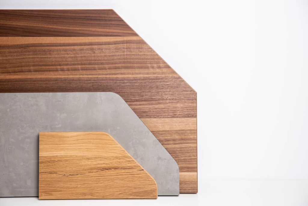 Drei Holzplatten-Zuschnitte in Sonderformen mit abgeschrägten Ecken in verschiedenen Dekoren vor weißem Hintergrund.