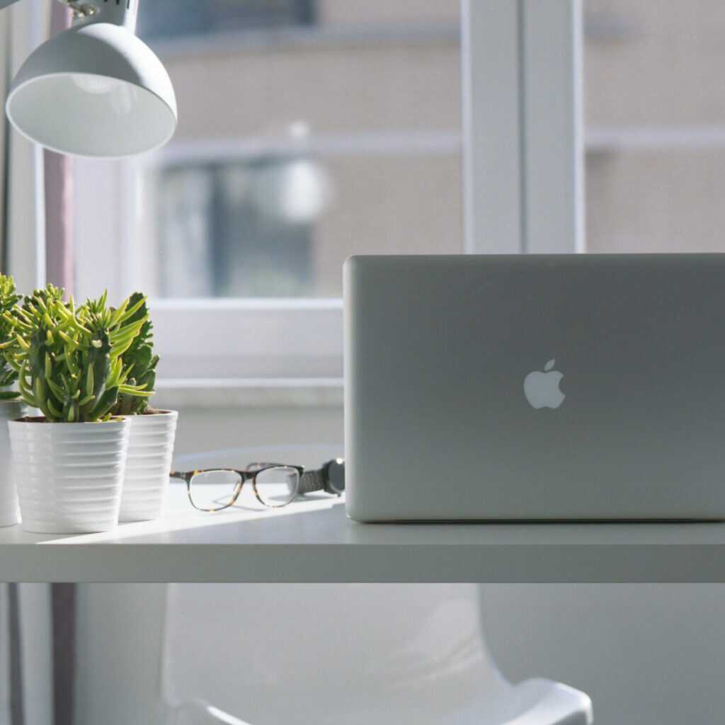 Weißer Tisch im Büro mit Laptop und Pflanzen