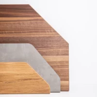 Drei Holzplatten-Zuschnitte in Sonderformen mit abgeschrägten Ecken in verschiedenen Dekoren vor weißem Hintergrund.